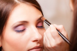 Makeup artist applying with brush cosmetic on eyebrow of woman